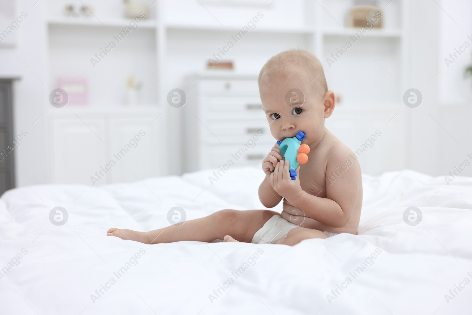 Photo of Cute little baby with rattle on bed indoors, space for text