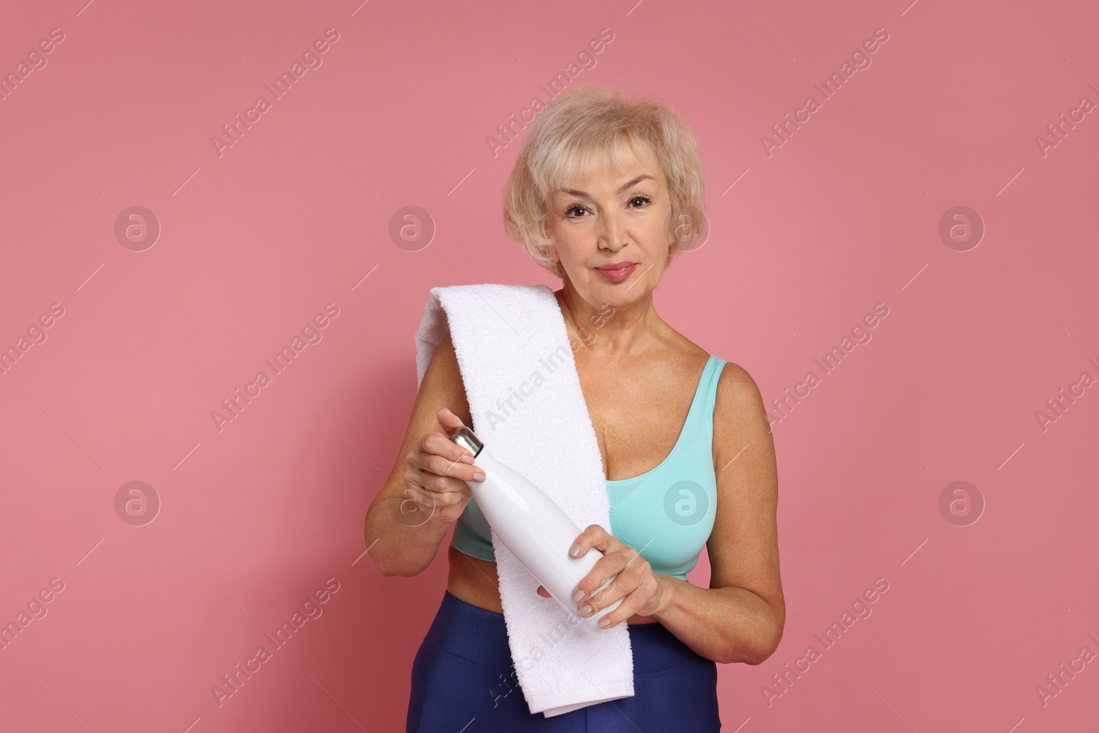 Photo of Senior woman with towel and water on pink background