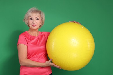 Photo of Senior woman with fitness ball on green background