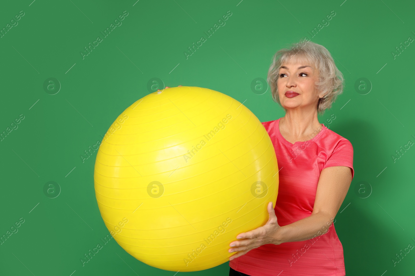 Photo of Senior woman with fitness ball on green background