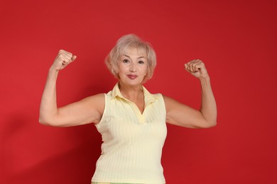 Photo of Senior woman exercising on red background. Healthy lifestyle