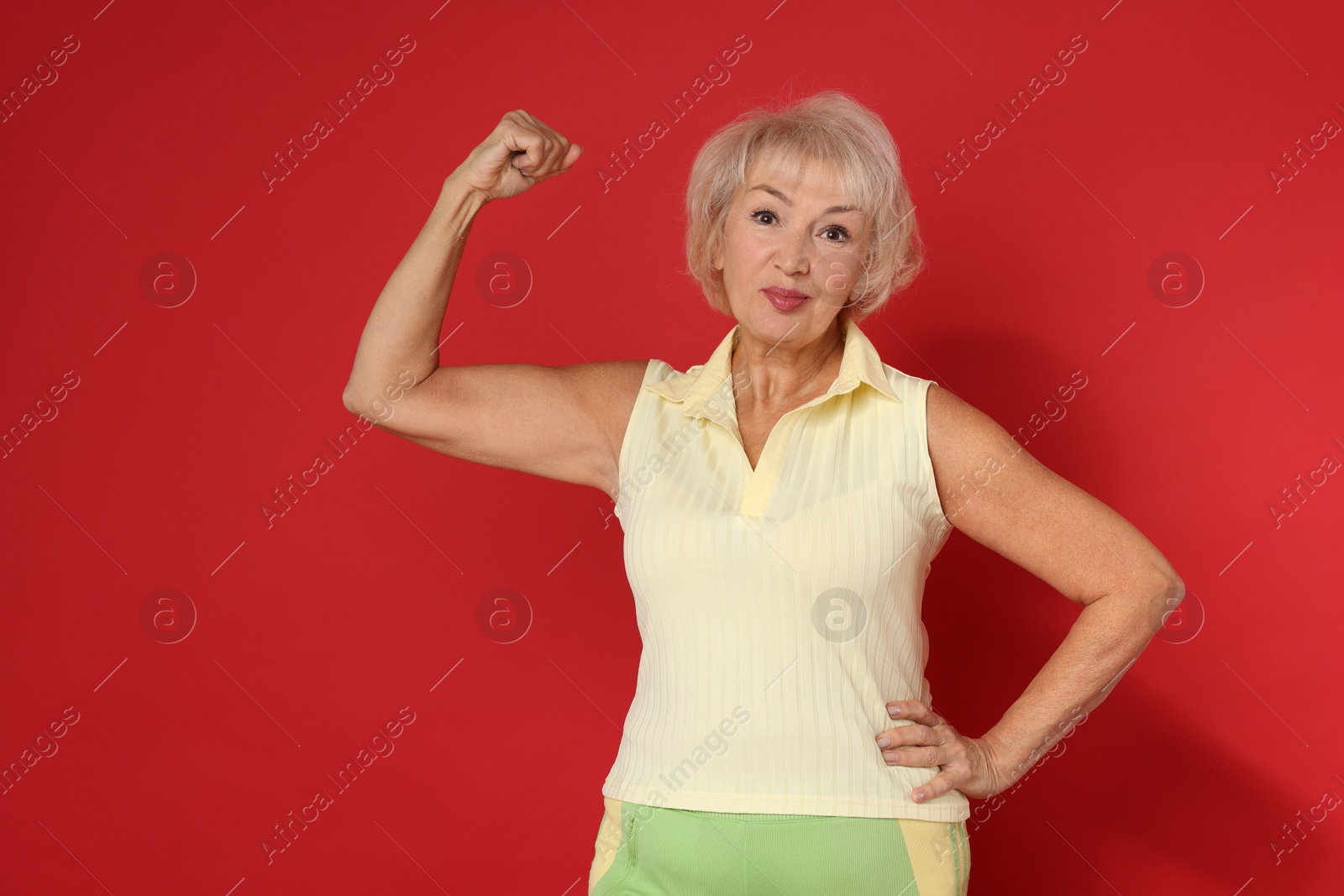 Photo of Senior woman exercising on red background. Healthy lifestyle