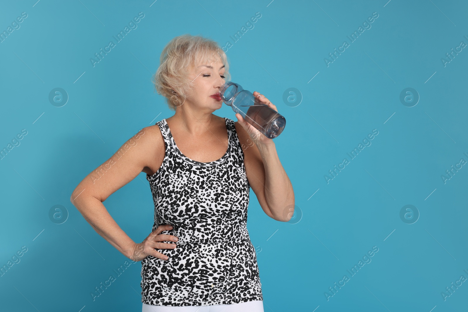 Photo of Senior woman with water on light blue background, space for text