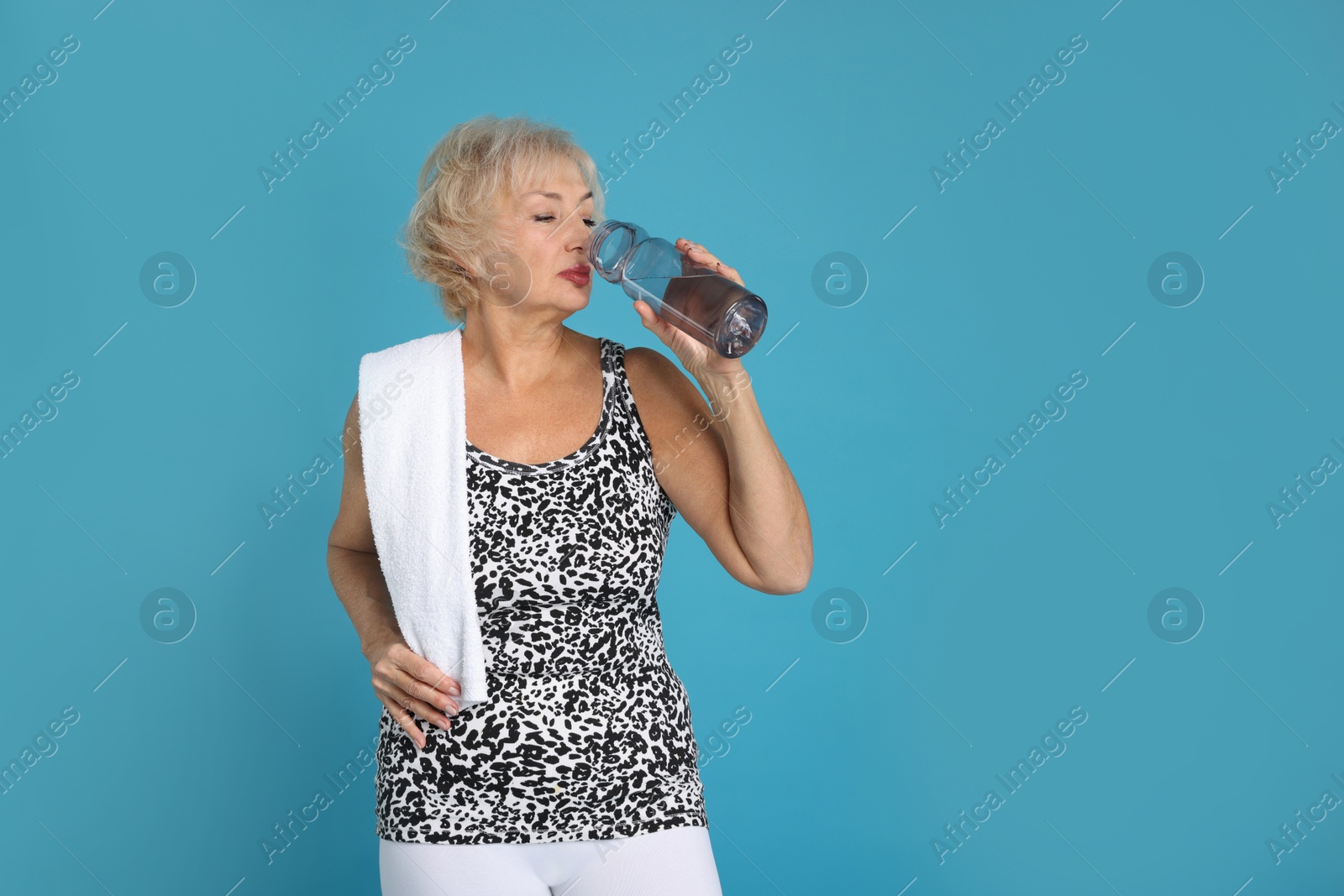 Photo of Senior woman with towel and water on light blue background, space for text