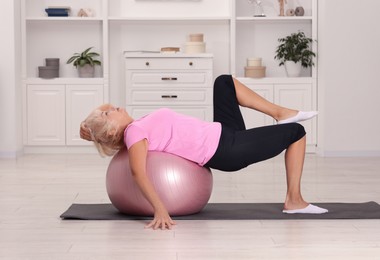 Photo of Senior woman exercising with fitness mat and ball at home