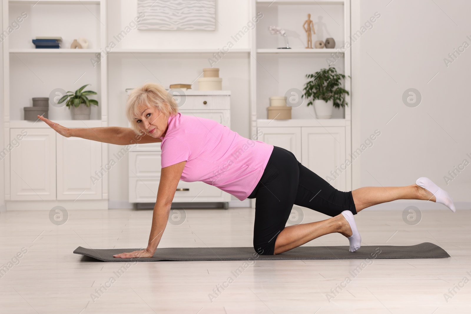 Photo of Senior woman exercising with fitness mat at home