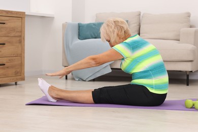 Photo of Senior woman exercising with fitness mat at home