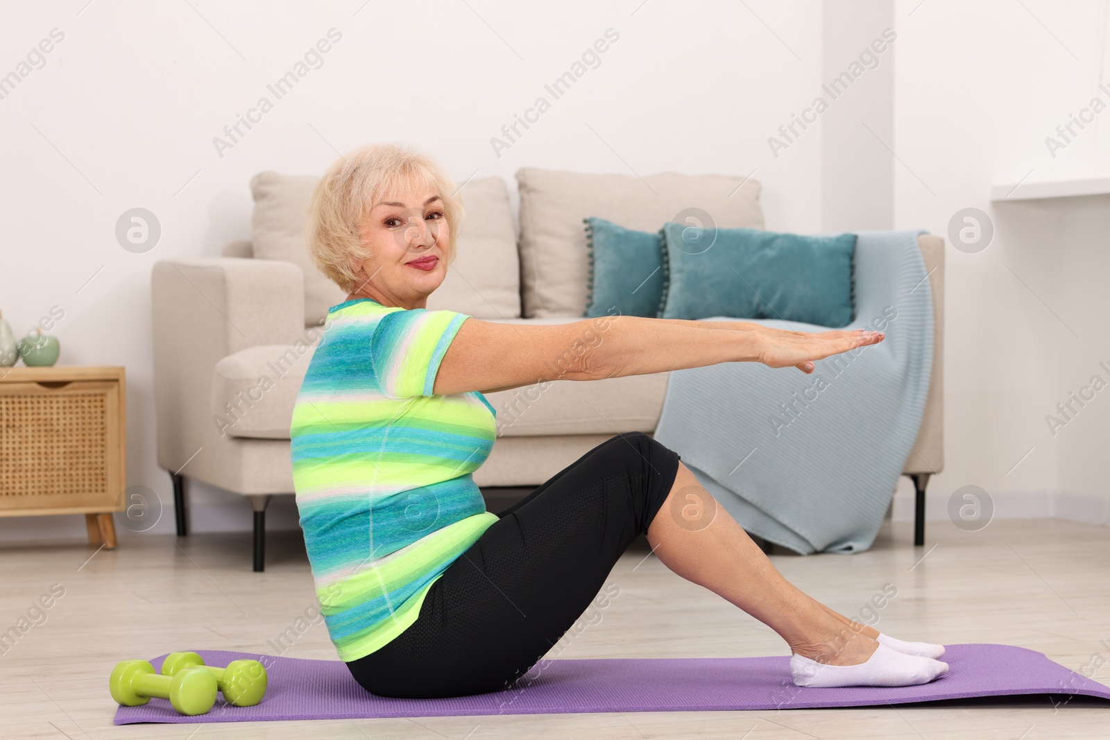 Photo of Senior woman exercising with fitness mat at home