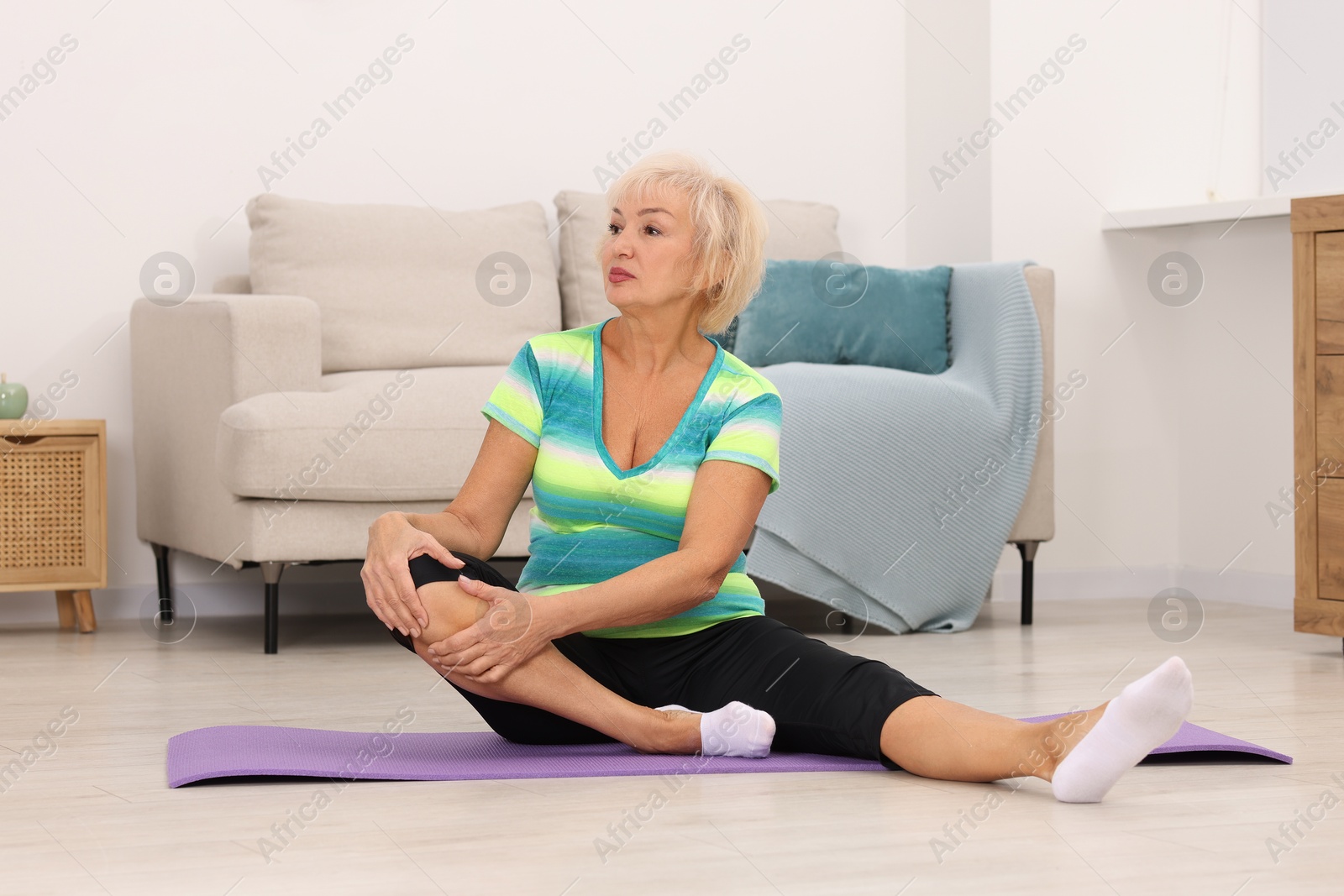 Photo of Senior woman exercising with fitness mat at home