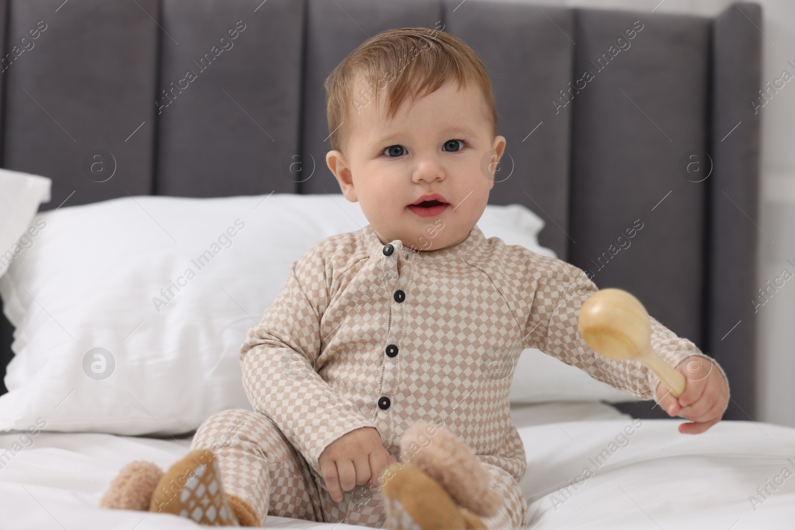 Photo of Little baby playing with toy on bed at home