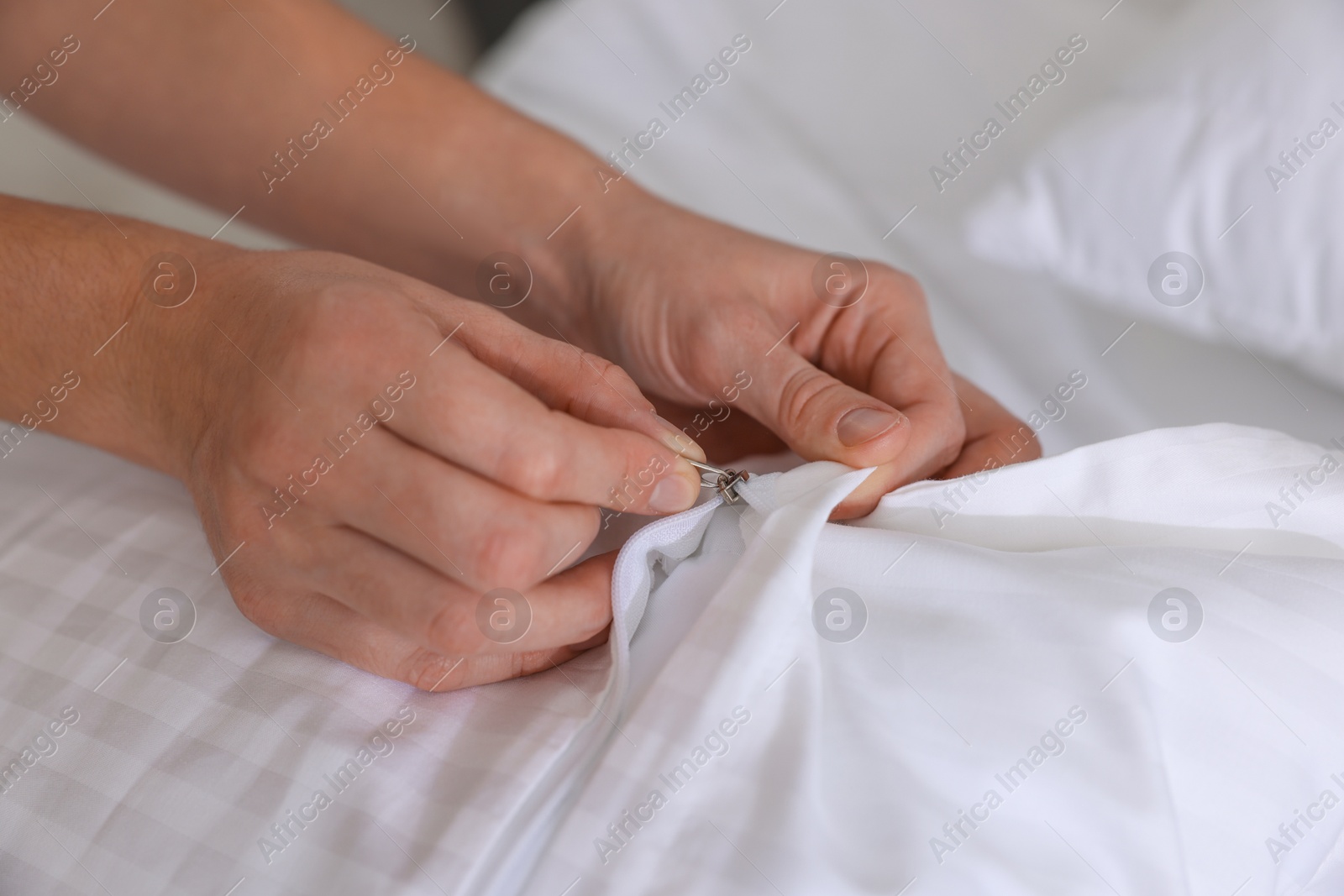 Photo of Woman changing clean bed linens at home, closeup