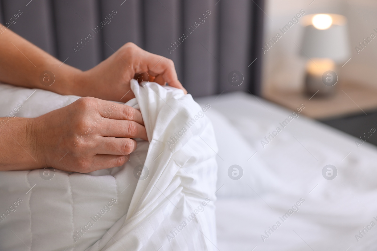 Photo of Woman changing clean bed linens at home, closeup