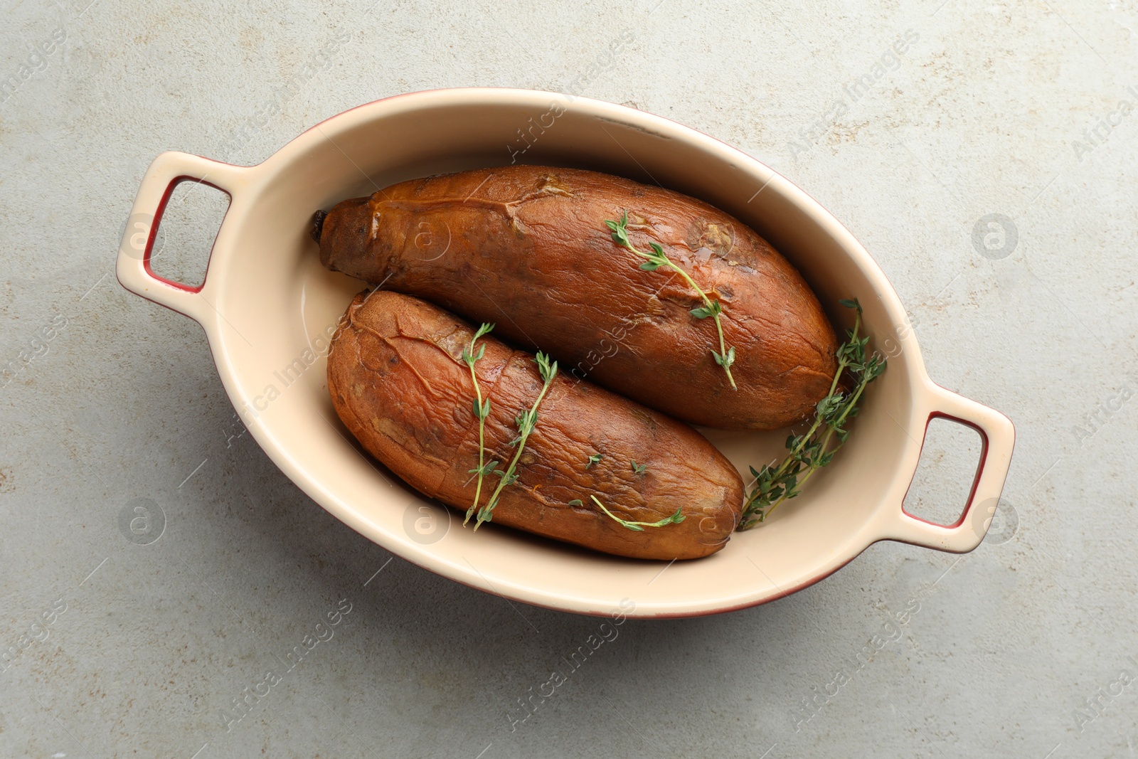 Photo of Tasty cooked sweet potatoes served with thyme on light grey table, top view