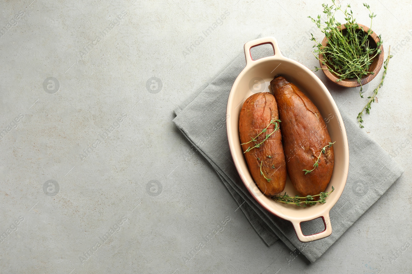 Photo of Tasty cooked sweet potatoes served with thyme on light grey table, flat lay. Space for text