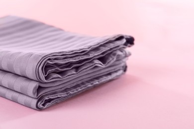 Photo of Stacked clean bed linens on pink background, closeup. Space for text