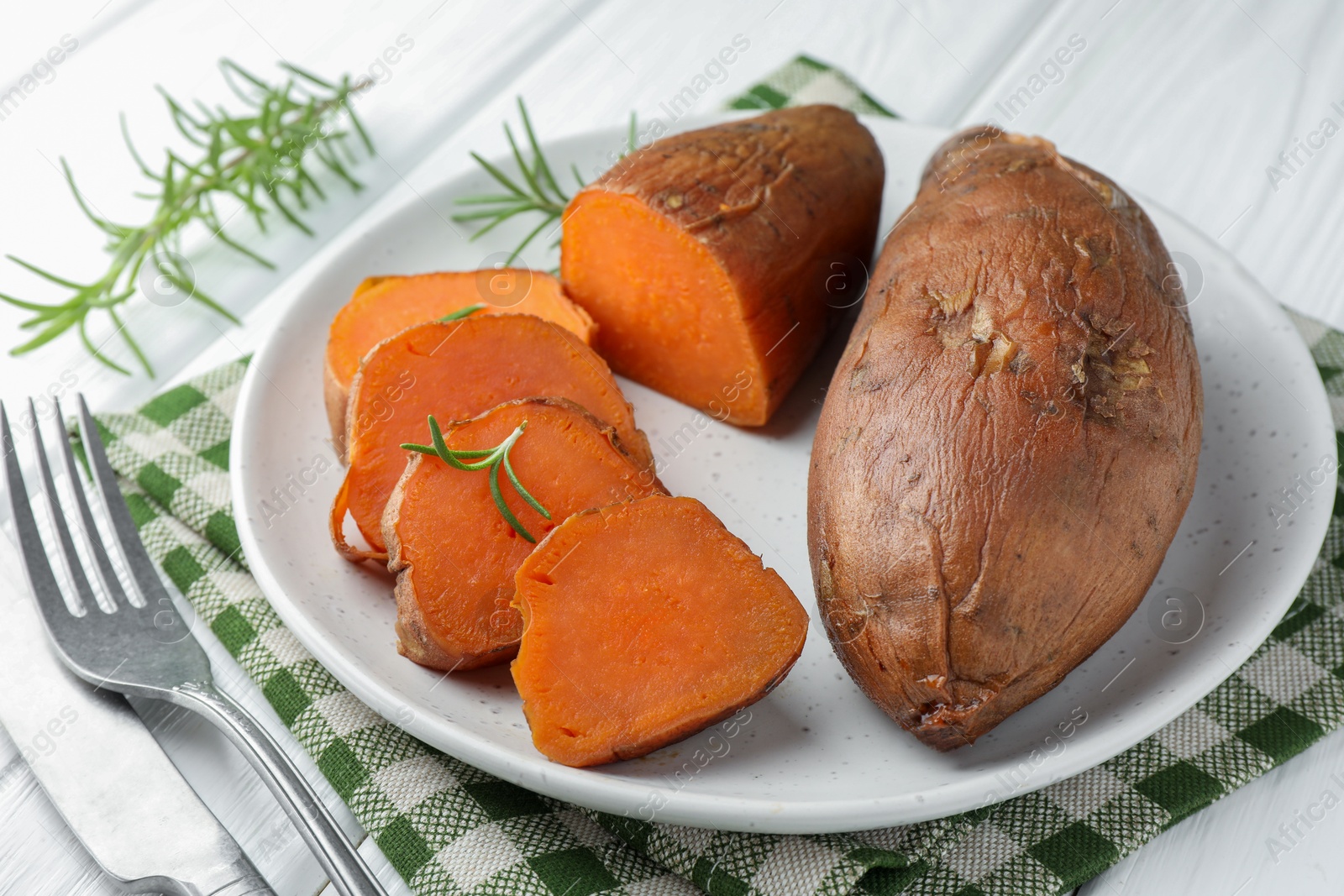 Photo of Tasty cooked sweet potatoes served with rosemary on table, closeup