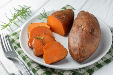 Photo of Tasty cooked sweet potatoes served with rosemary on table, closeup