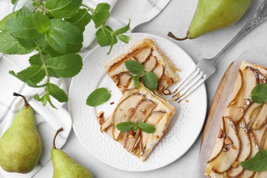 Photo of Pieces of tasty puff pastry pie with pears and mint on light grey table, top view