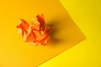 Orange crumpled paper on yellow background, space for text