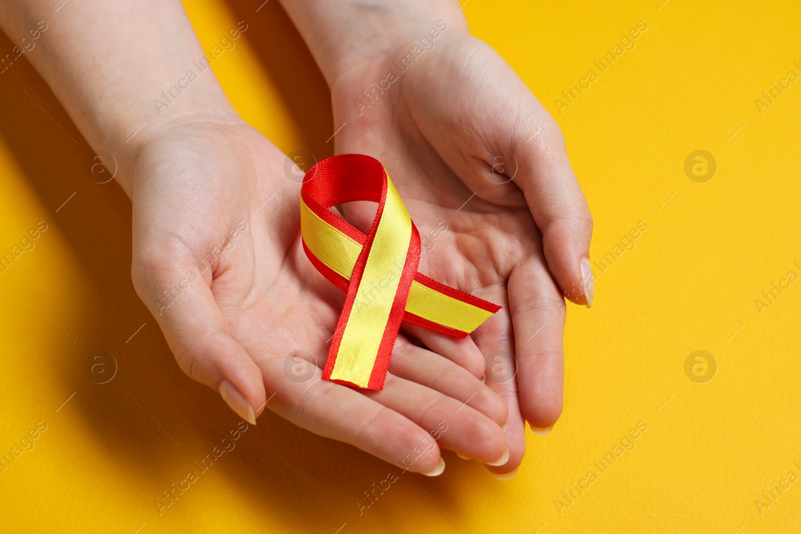 Photo of Woman with colorful ribbon on yellow background, closeup. Hepatitis C awareness