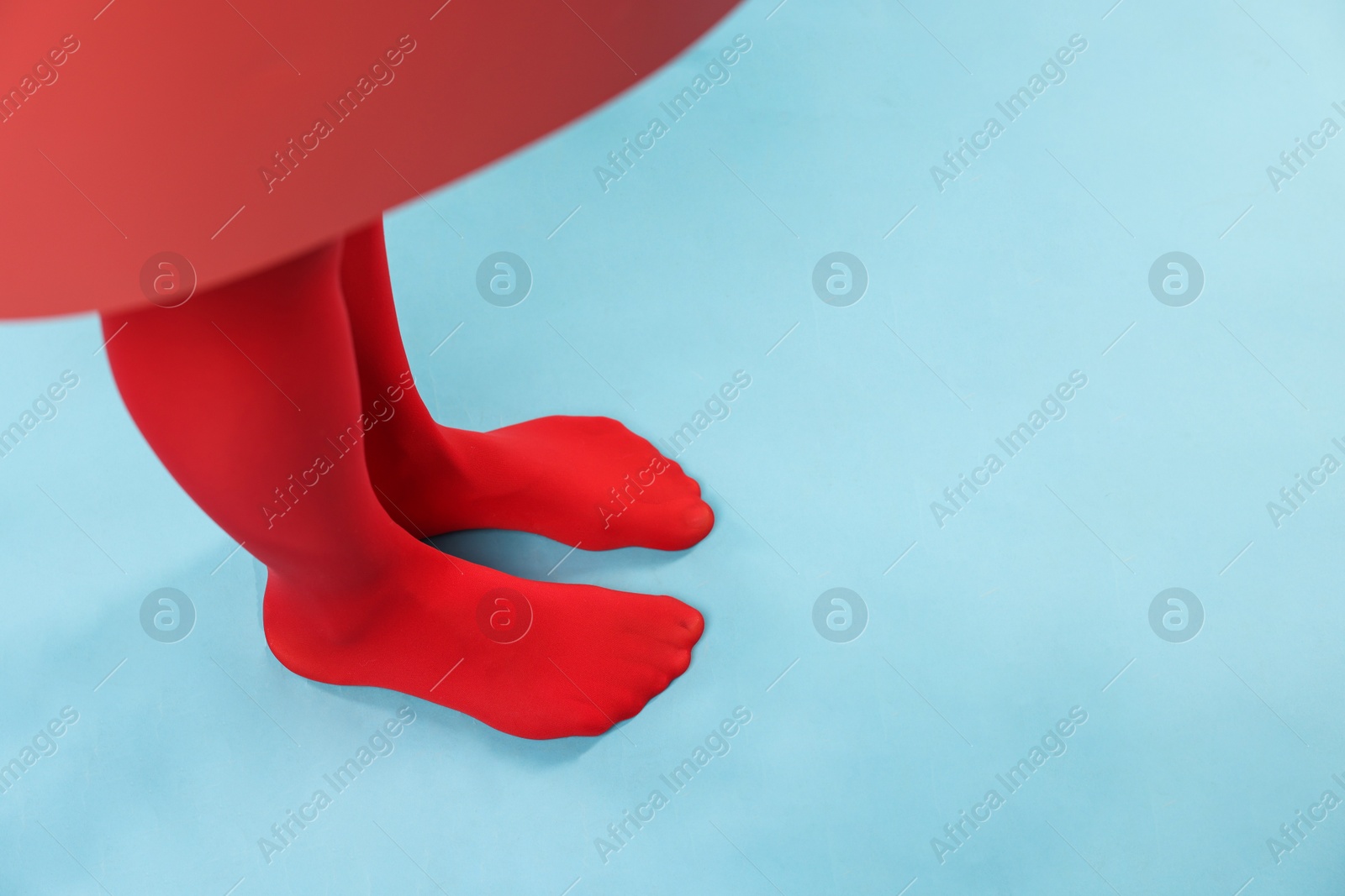 Photo of Young woman in red tights posing on light blue background, closeup. Space for text