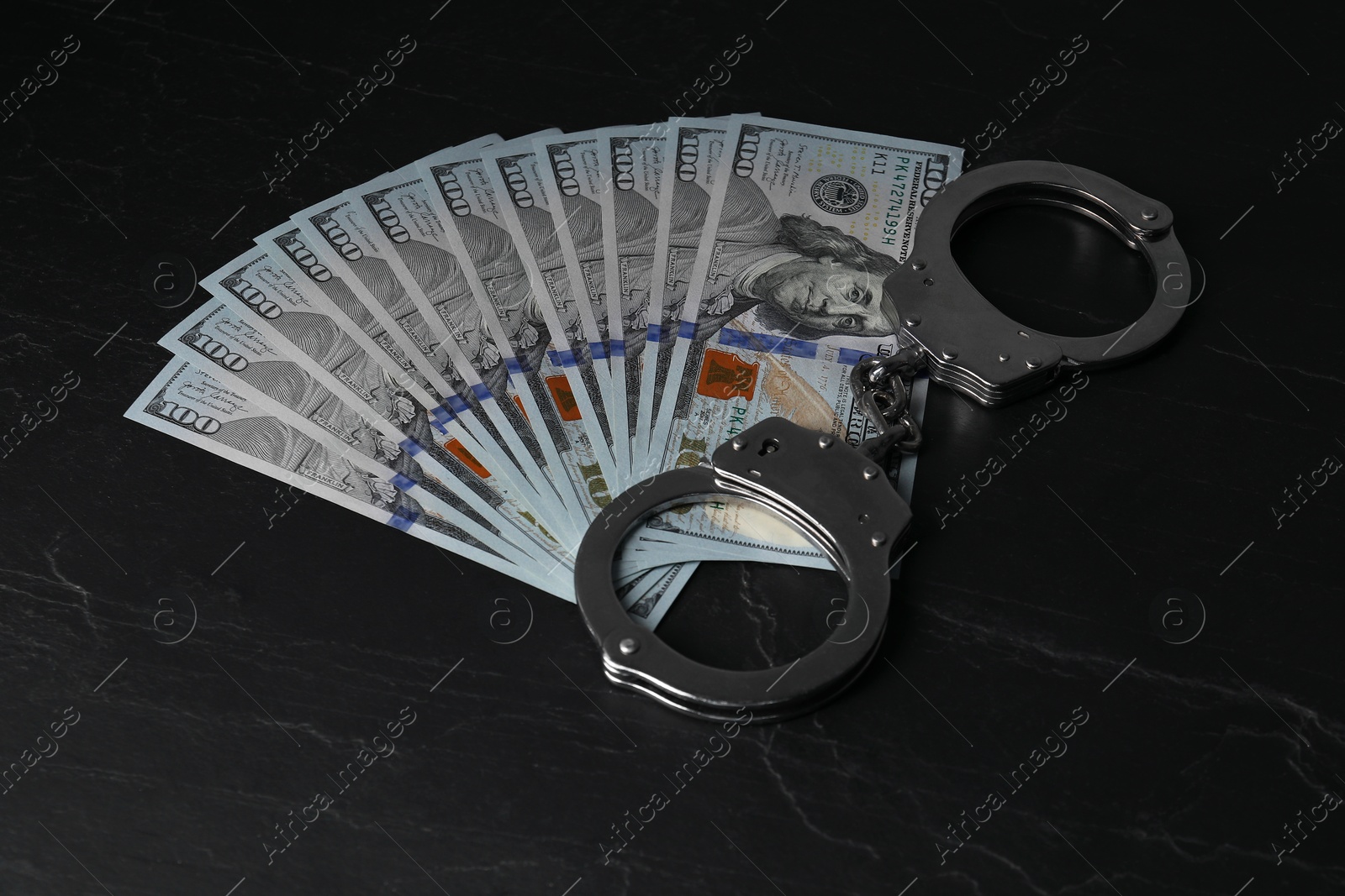 Photo of Corruption. Dollar banknotes and handcuffs on black table