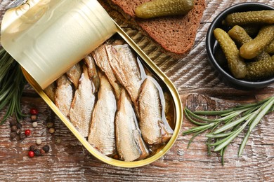 Photo of Tasty sprats in tin can served on wooden table, flat lay