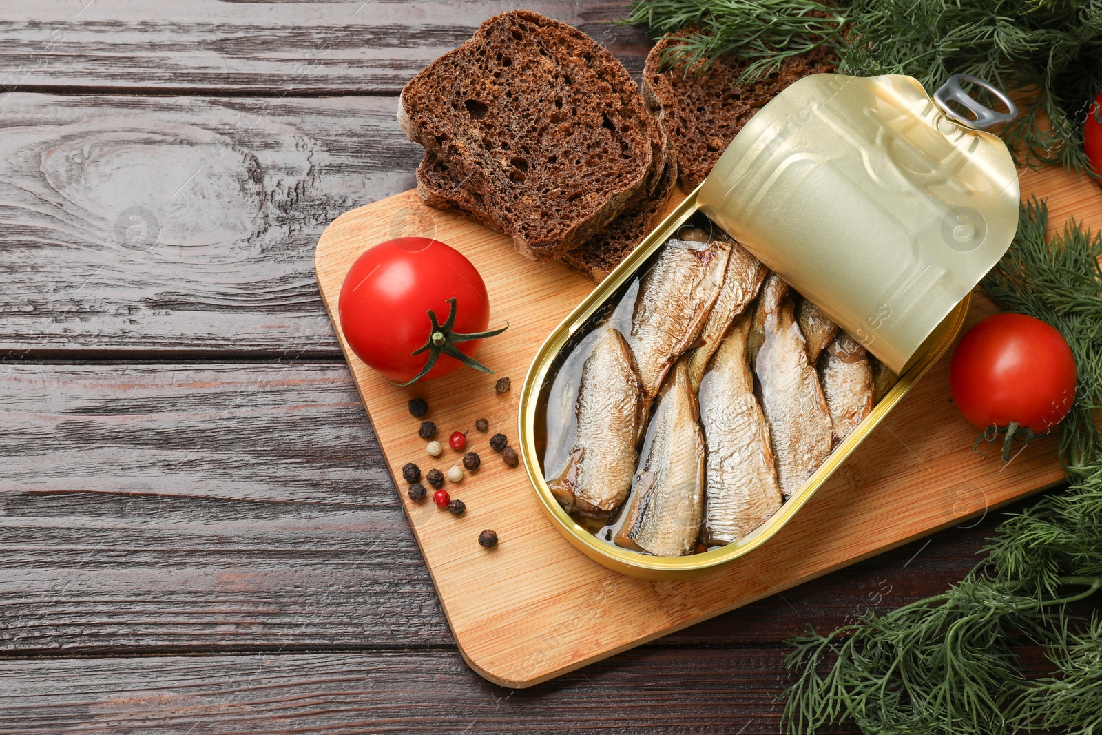 Photo of Tasty sprats in tin can served on wooden table, flat lay