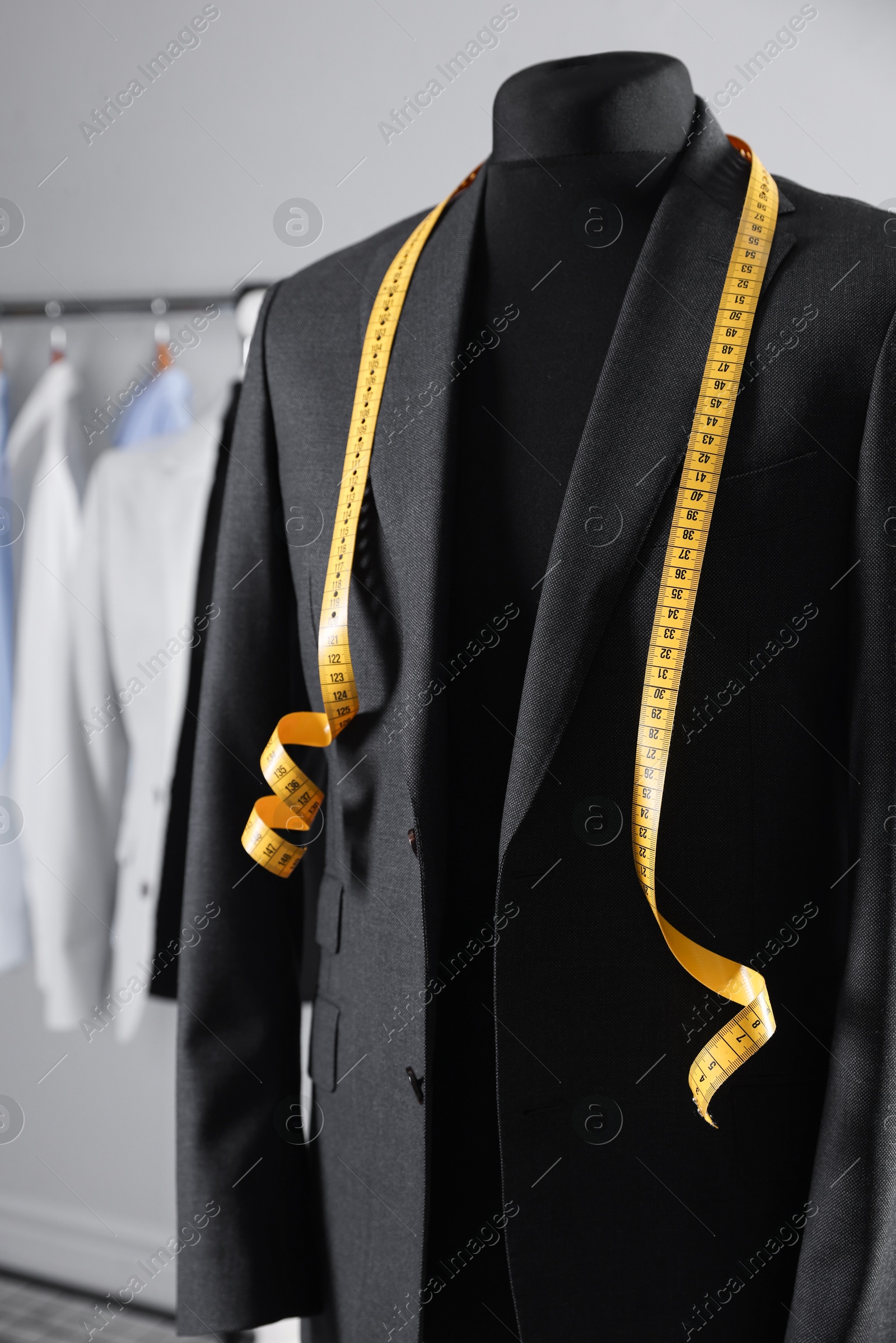 Photo of Male mannequin with jacket and measuring tape in tailor shop, closeup