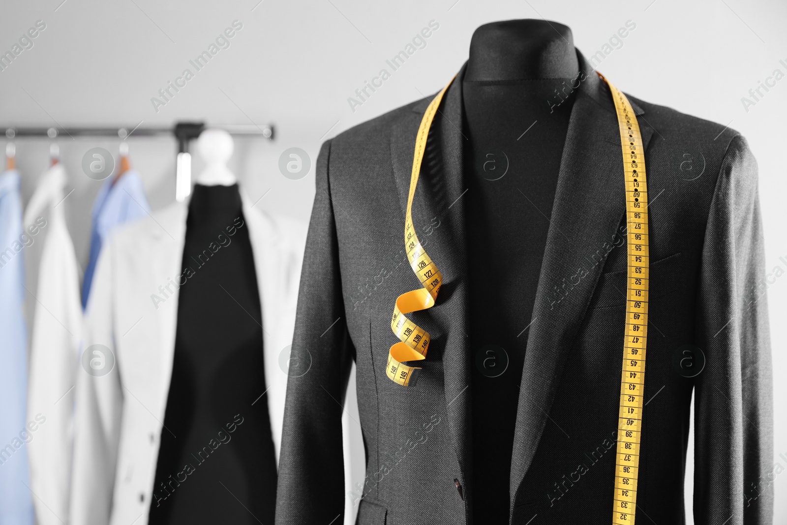 Photo of Male mannequin with jacket and measuring tape in tailor shop, closeup