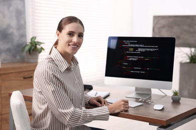 Photo of Programmer working on computer at wooden desk indoors