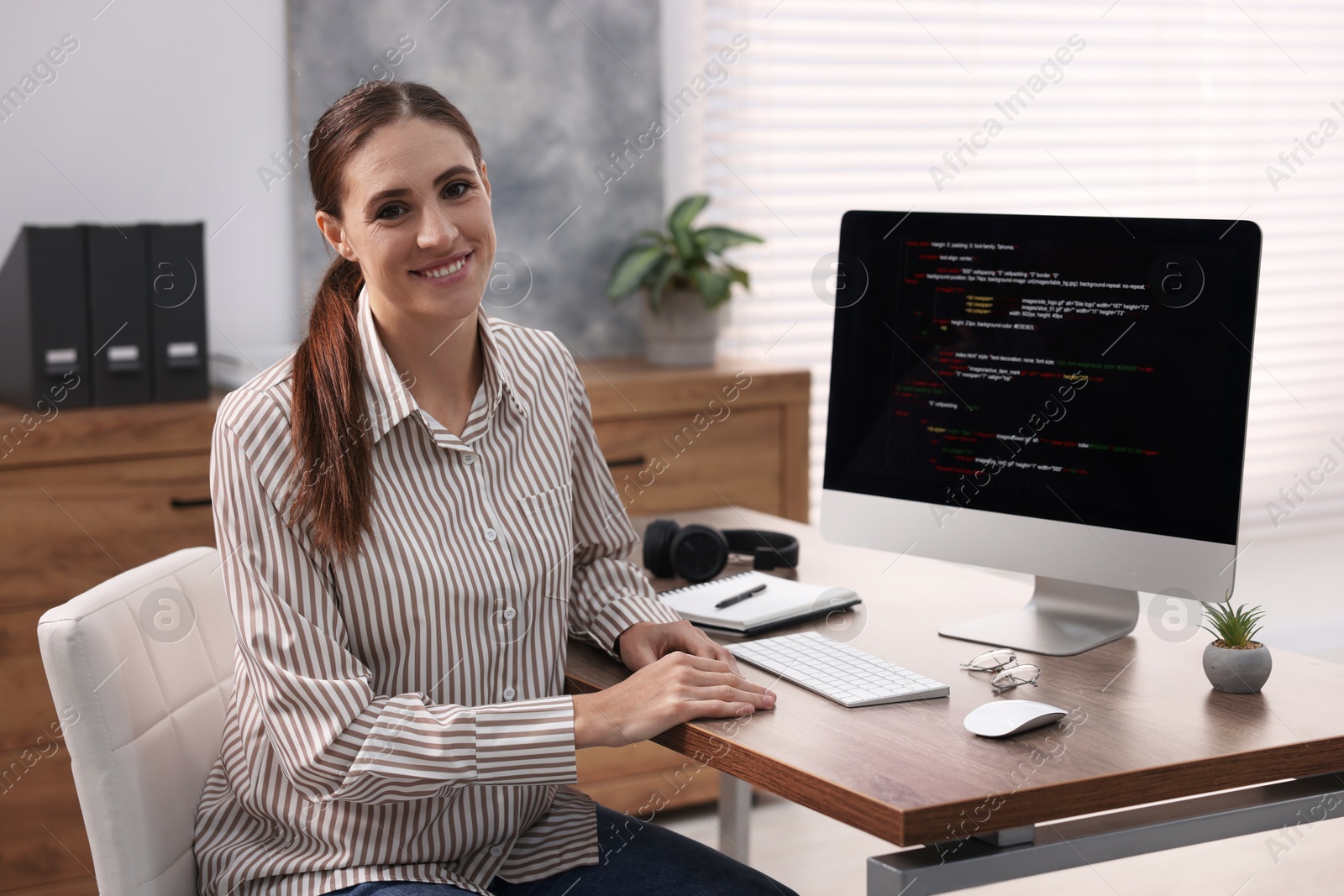 Photo of Programmer working on computer at wooden desk indoors