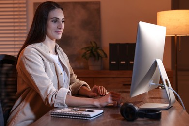 Photo of Programmer working on computer at wooden desk indoors