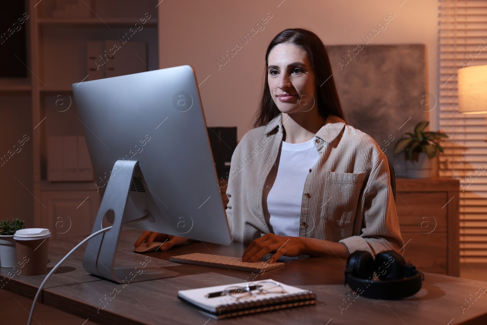 Photo of Programmer working on computer at wooden desk indoors