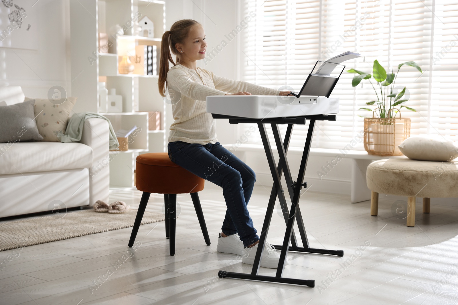 Photo of Cute girl playing synthesizer at home. Electronic musical instrument