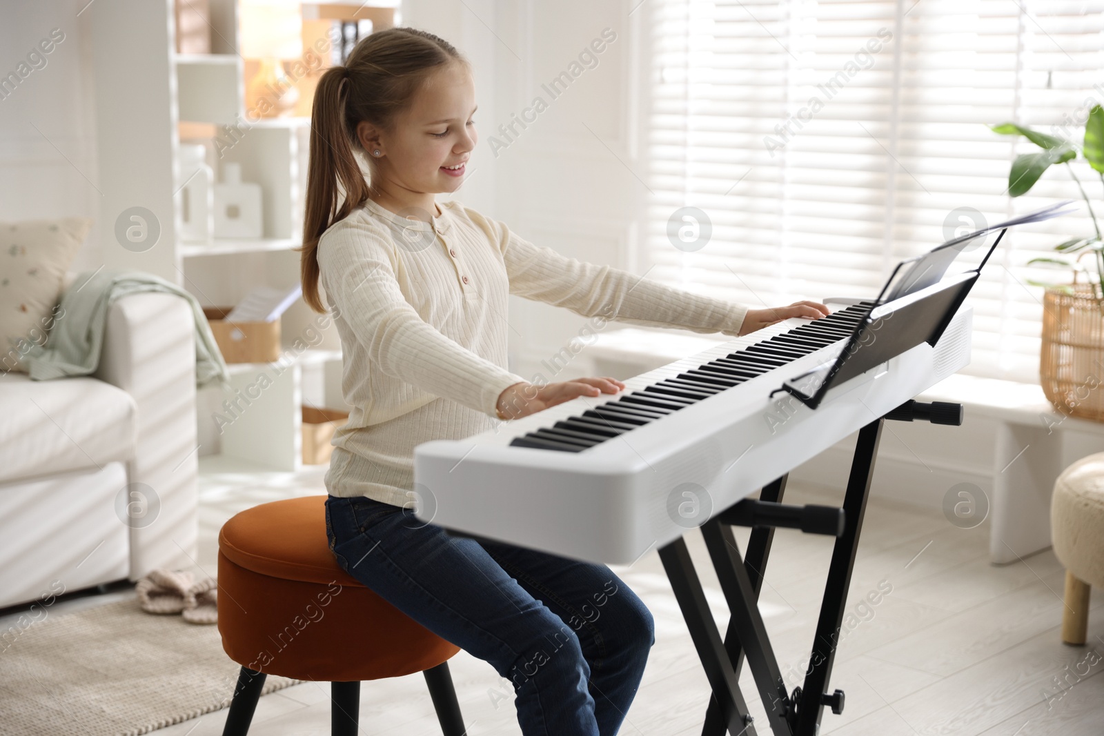 Photo of Cute girl playing synthesizer at home. Electronic musical instrument