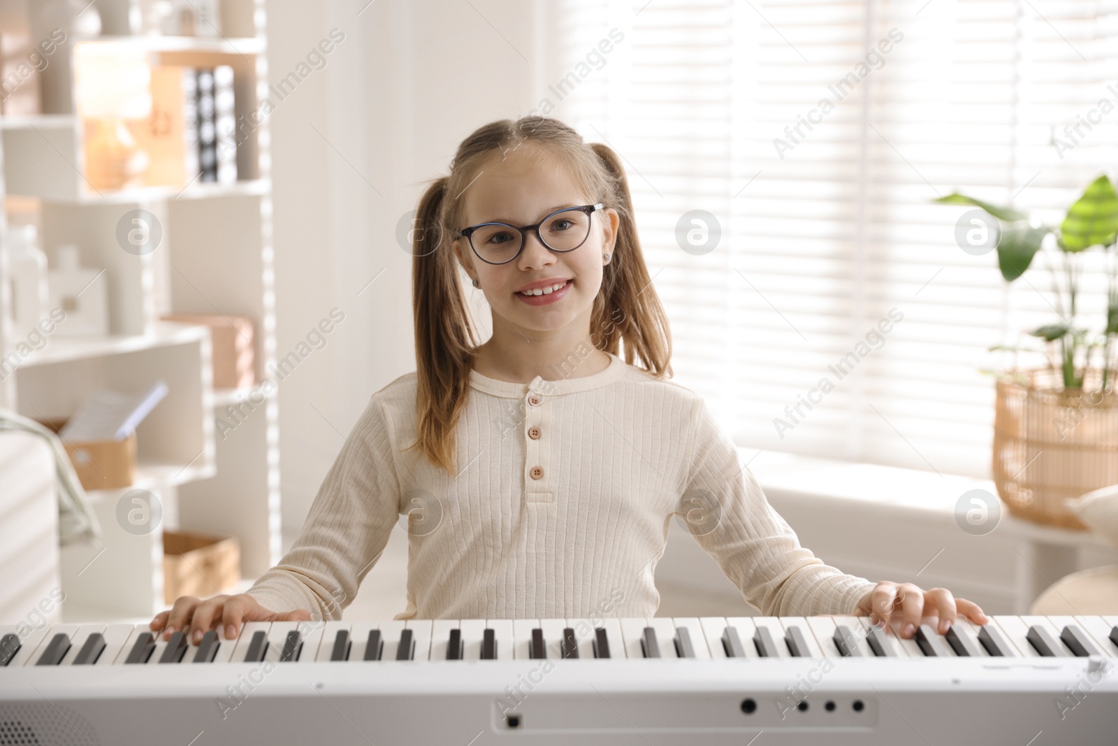 Photo of Cute girl playing synthesizer at home. Electronic musical instrument