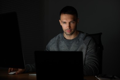 Photo of Programmer working on laptop indoors at night