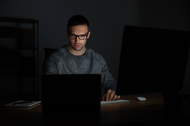 Photo of Programmer working on laptop indoors at night