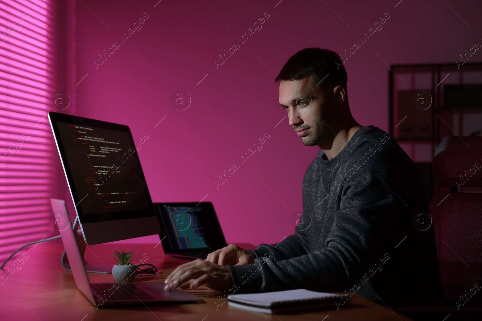 Photo of Programmer working on computer indoors at night