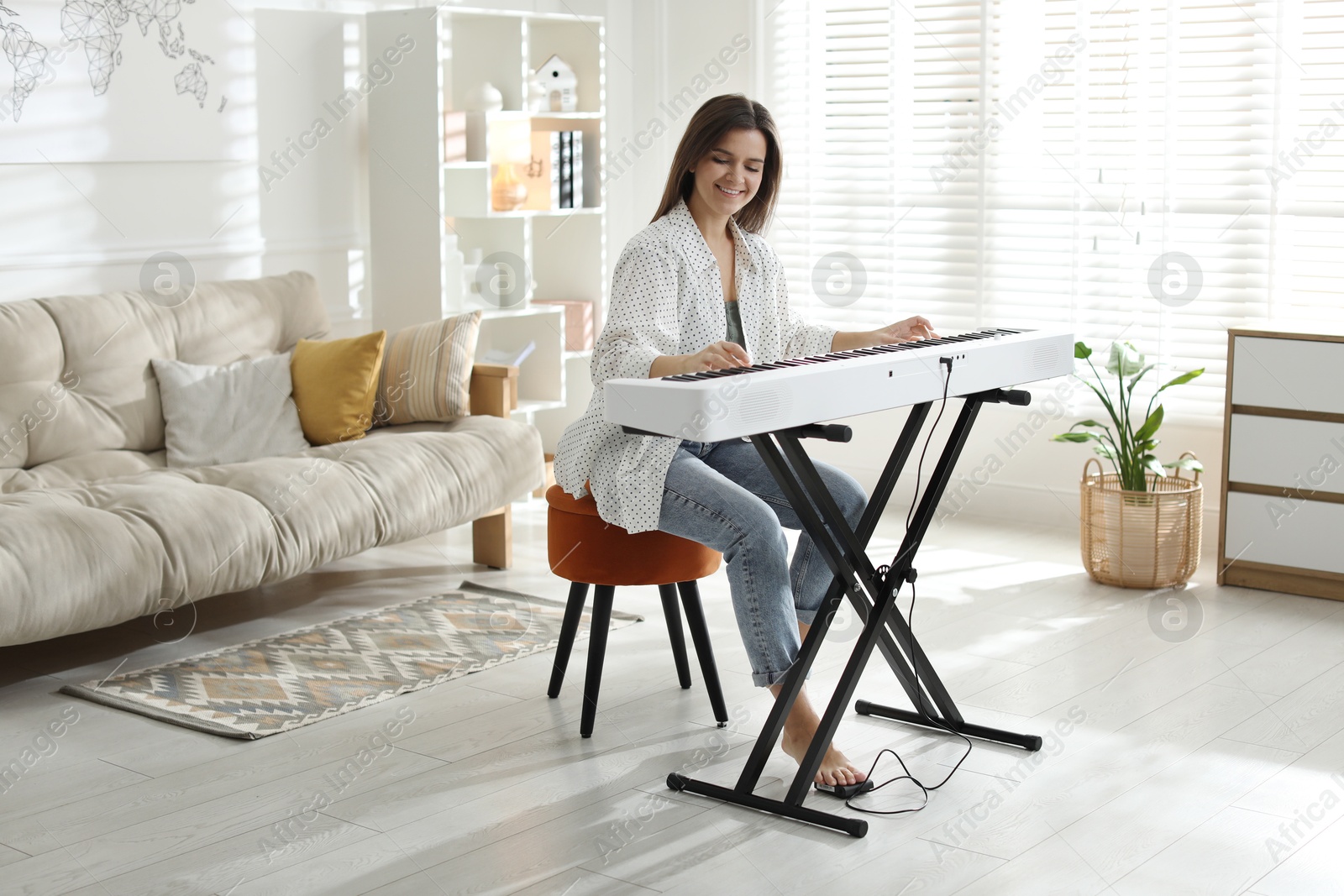 Photo of Smiling woman playing synthesizer at home. Electronic musical instrument