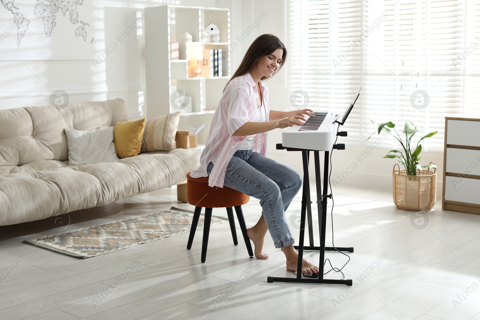 Photo of Smiling woman playing synthesizer at home. Electronic musical instrument