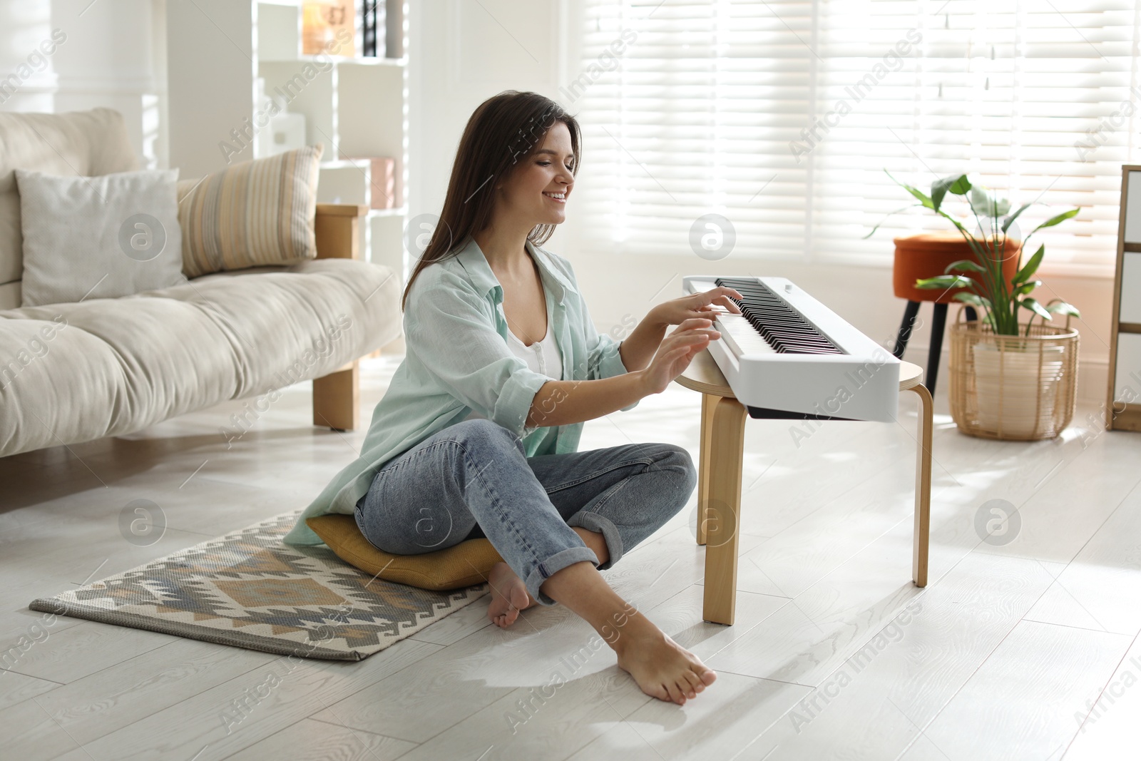 Photo of Smiling woman playing synthesizer on floor at home