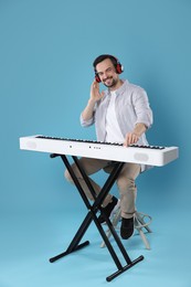 Photo of Smiling man playing synthesizer on light blue background