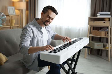 Photo of Man playing synthesizer at home. Electronic musical instrument