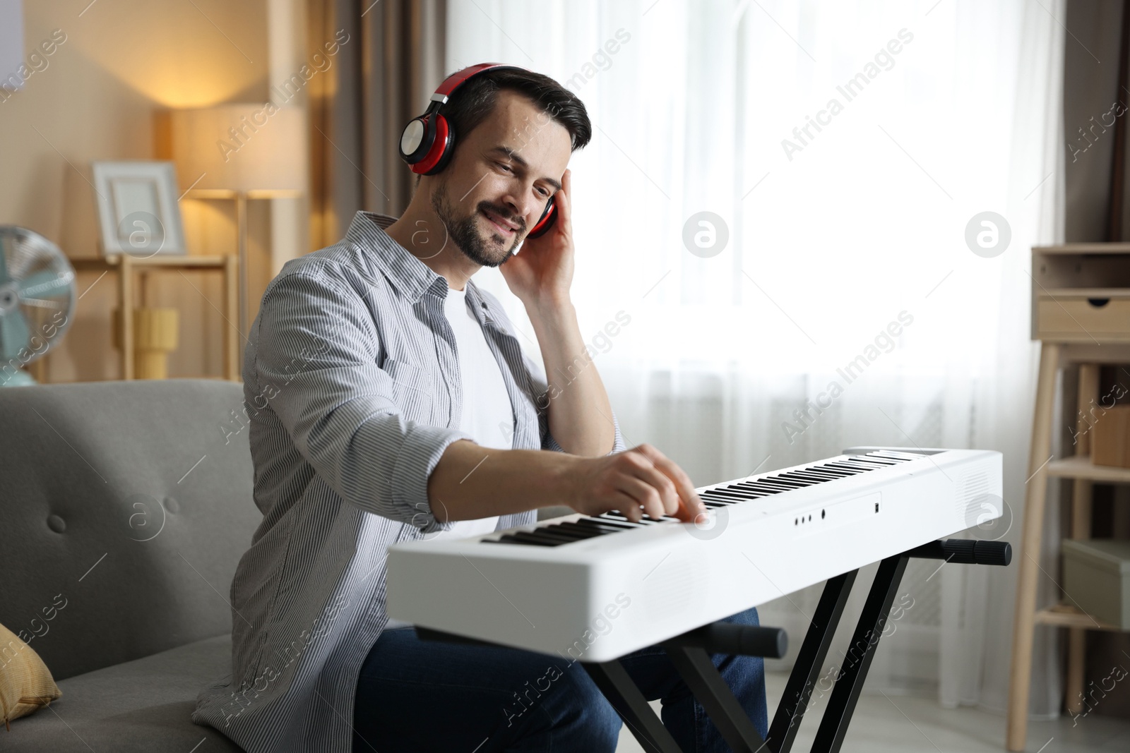 Photo of Man in headphones playing synthesizer at home