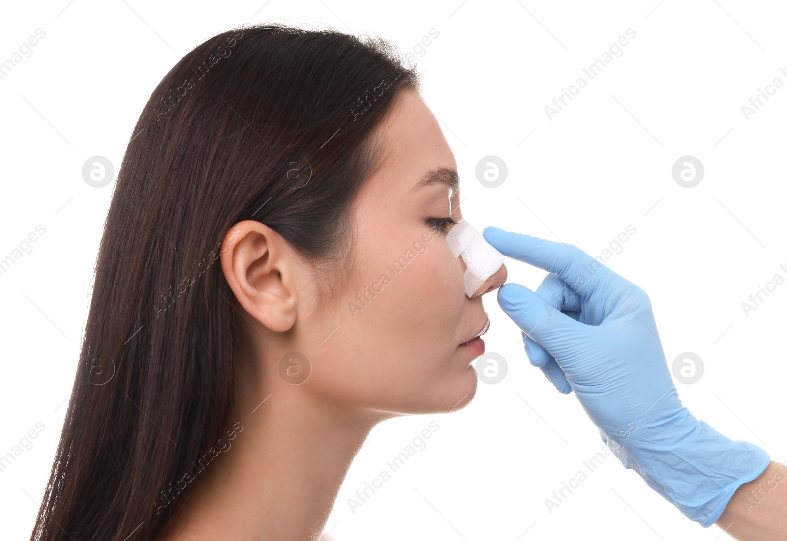 Photo of Doctor checking patient's nose after plastic surgery operation on white background, closeup