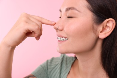 Photo of Woman touching her nose on pink background, closeup