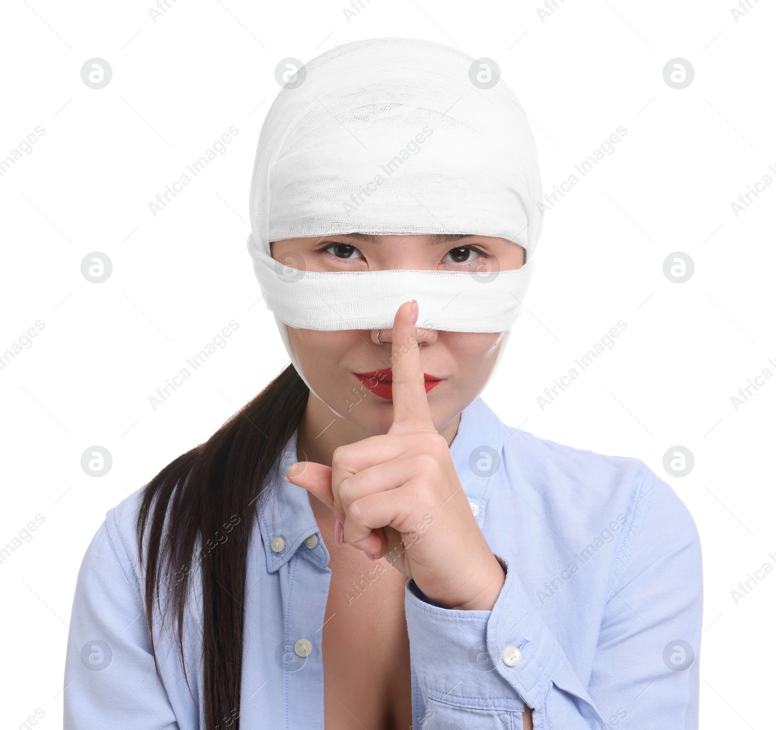 Photo of Woman with nose wrapped in medical bandage after plastic surgery operation making silent gesture on white background