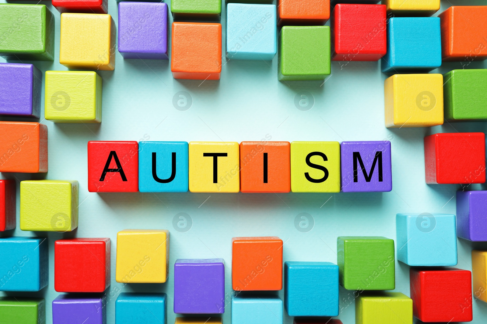 Photo of Word Autism made with colorful cubes on light blue background, flat lay